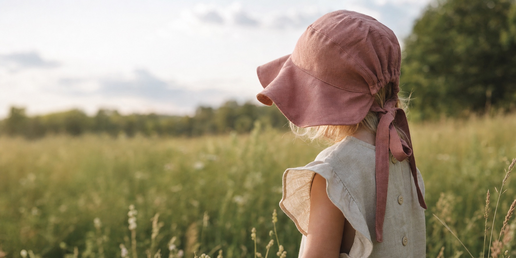 Child wearing a dusty rose AYOMY linen bonnet outdoors